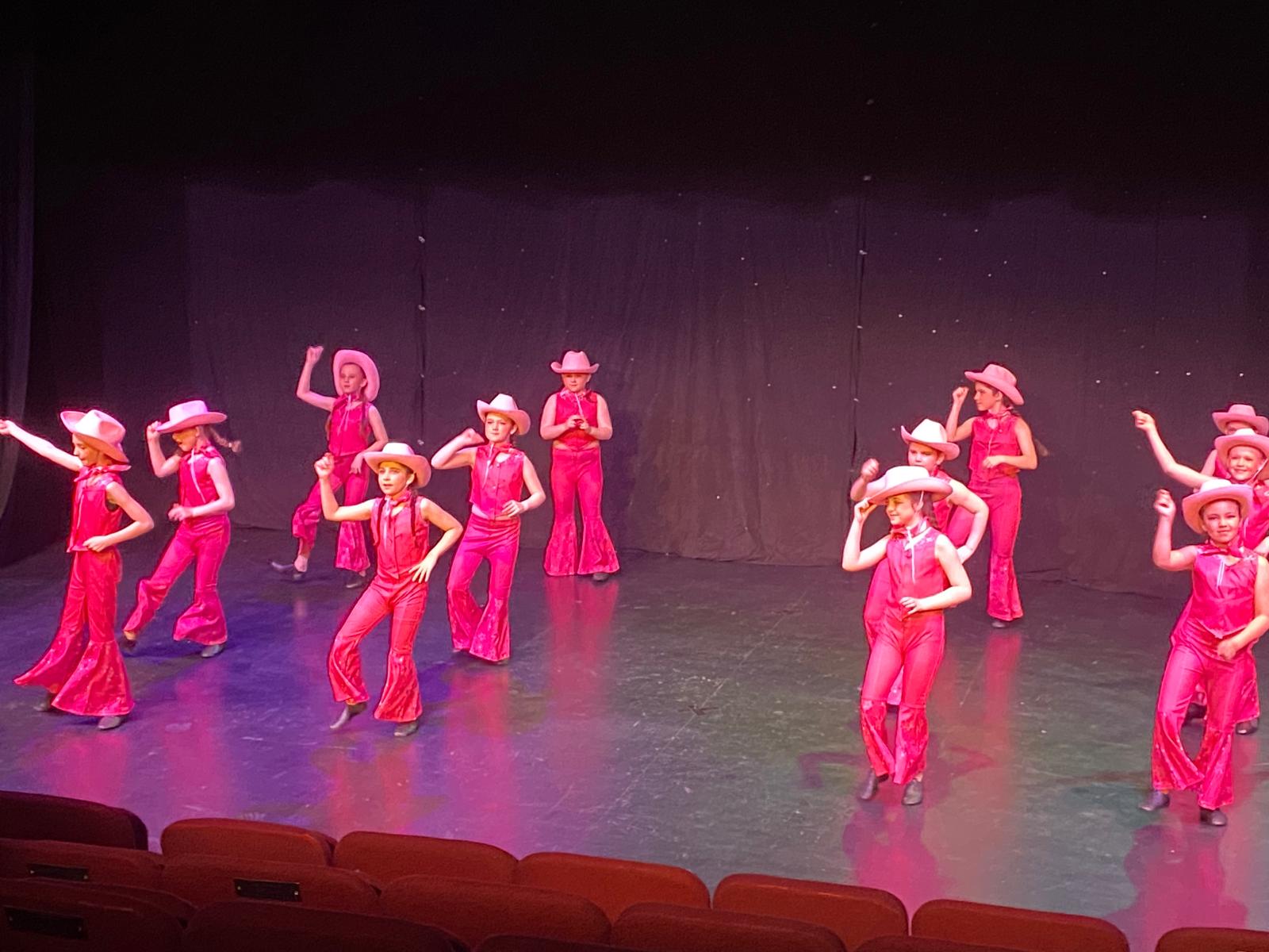 Tap dance students performing synchronized routine on stage